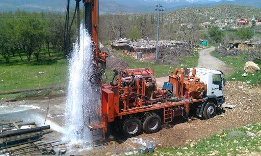 Water surging from a newly drilled borehole beside a Phreatic drilling rig