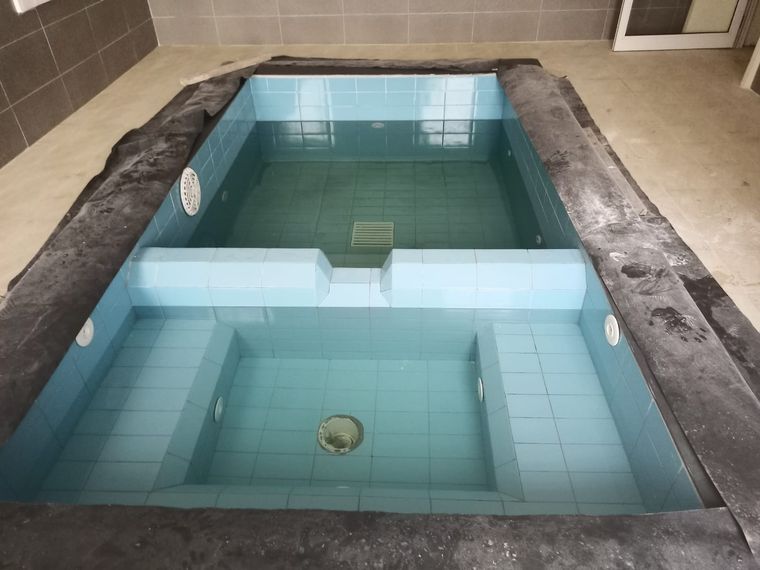 A finished swimming pool with clear blue water and tiled steps